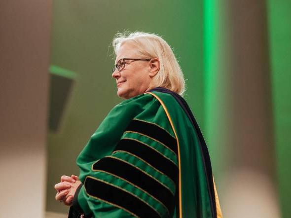 网赌平台 President Joanie Mahoney stands in commencement regalia.