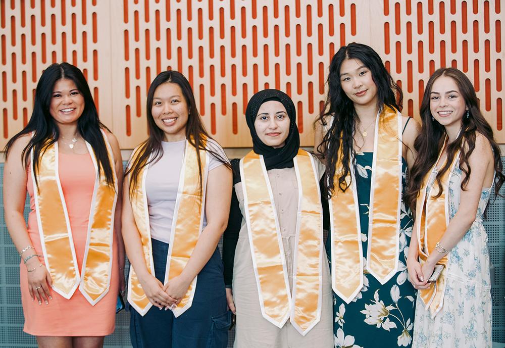 Five female students wearing dresses and gold sashes